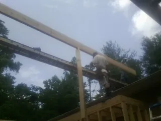 Carpenter setting a ridge beam over a new addition frame — Ice Dam Removal by Roofing Brothers in Creekside