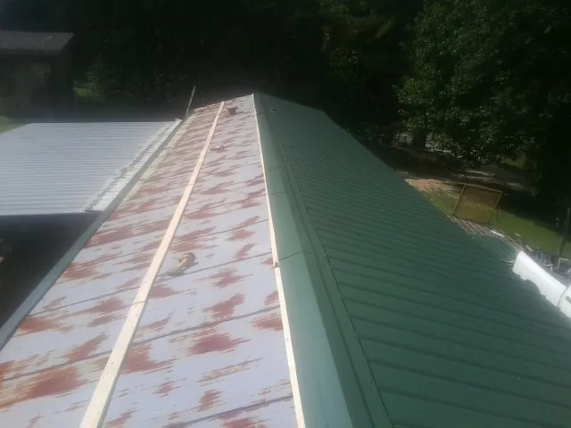 Old rusted panels beside newly installed green metal roofing — Wind Damage Roof Repair by Roofing Brothers in Creekside