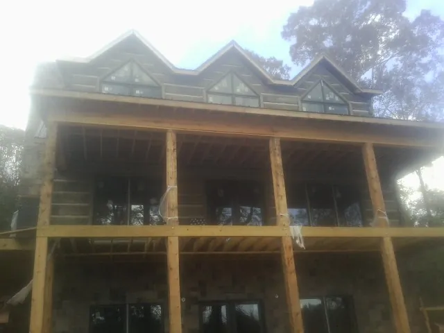 Dormers and porch framing on a large log home under construction — Roof Coating work by our crew in Creekside