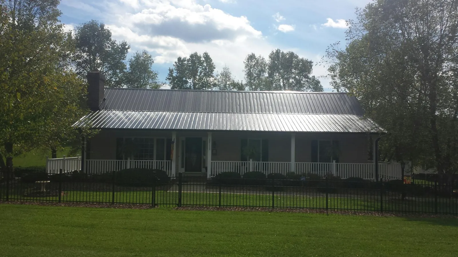 Gray metal roof on a brick ranch with a full width front porch — Gutter Guard Installation work by our crew in Creekside