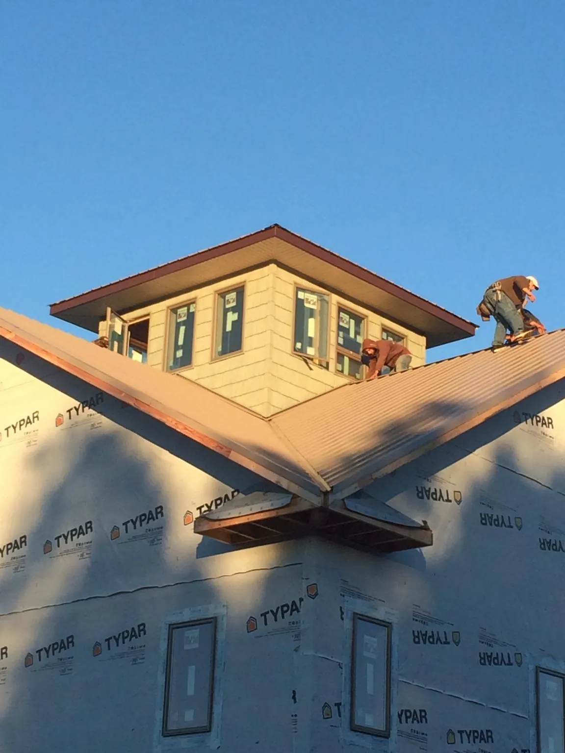Roofers working around a rooftop cupola on a new metal roof at sunset — Roof Waterproofing in Creekside by Roofing Brothers